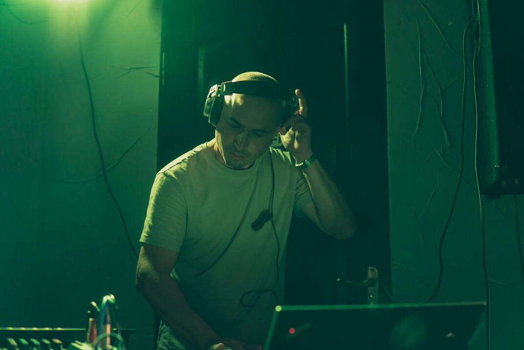 Portrait of an older white man with a grey beard wearing headphones in a sound studio